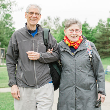 Annette and her husband, Donald, arm in arm on a park path smiling